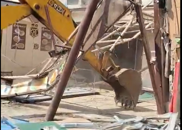 Heavy machinery in action: A JCB excavator pulls down an illegal metal shed in Kausarbag, Pune, as part of the PMC's demolition drive, leaving a pile of twisted metal and construction debris on the site.
